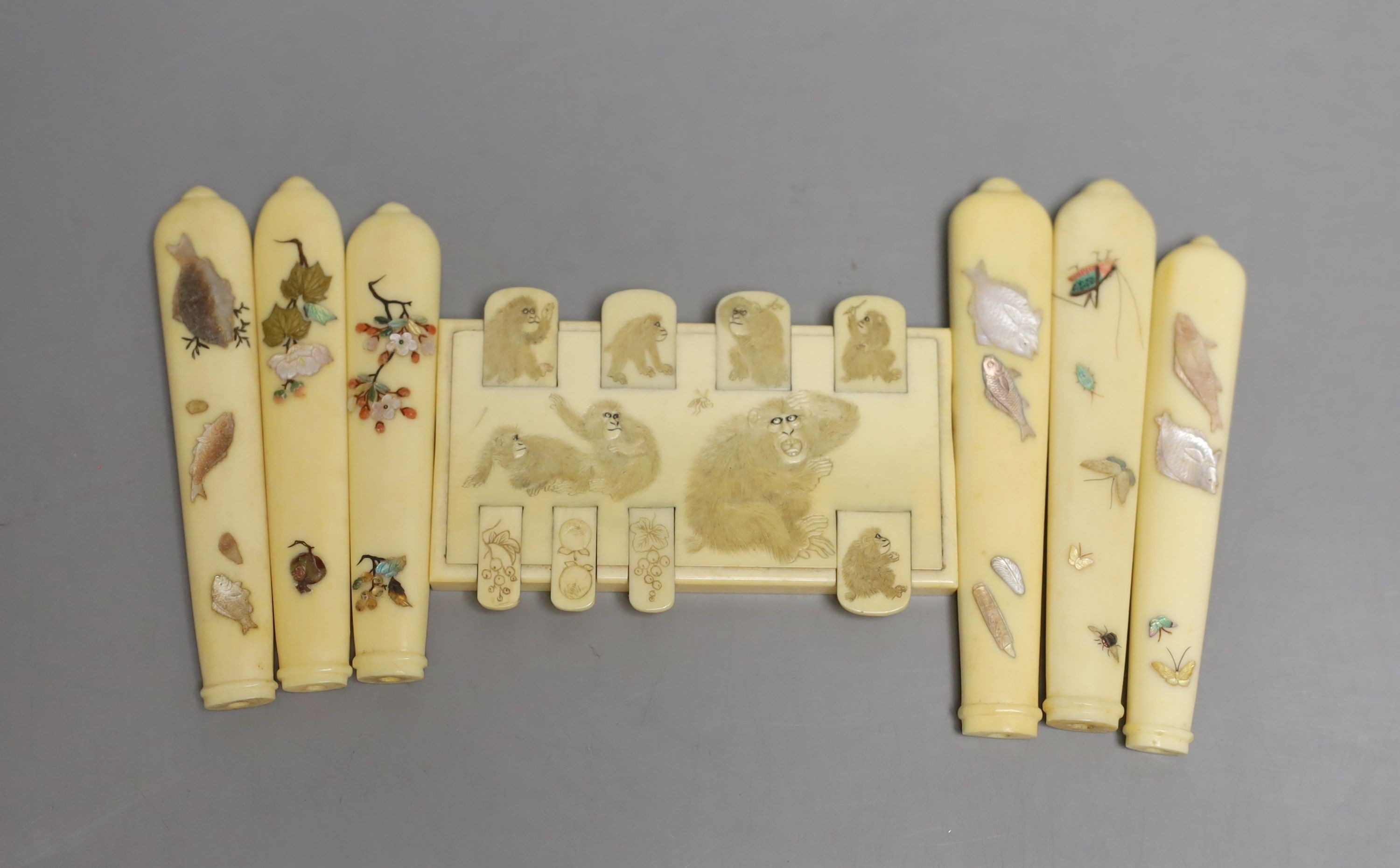 A carved ivory Japanese bezique marker and six Shibayama style ivory handles, Meiji period marker 9cms wide x 6 high.